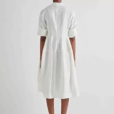 Vestido branco de tecido leve e corte evasê visto de costas.