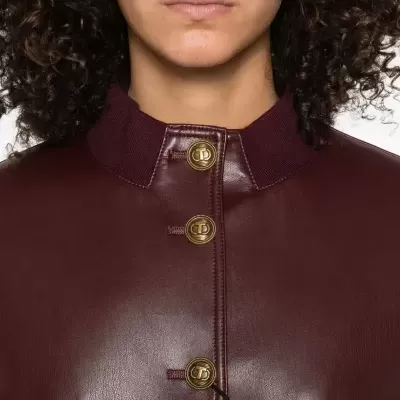 Casaco borgonha em couro com botões dourados e gola canelada.