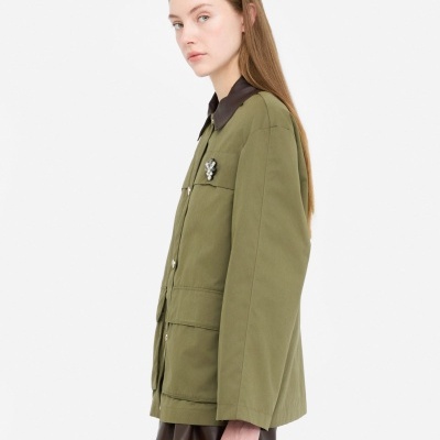 Casaco verde com colarinho castanho e broche em forma de flor