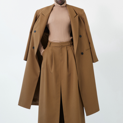 Modelo vestindo casaco longo camel, calças largas camel e camisola rosa de gola alta