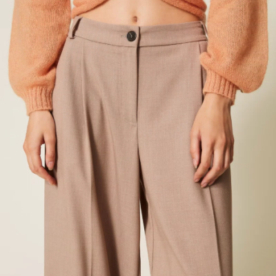 Calças bege largas com botão preto e camisola de malha laranja