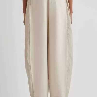 Calças largas bege com sapatos pretos vistas de costas