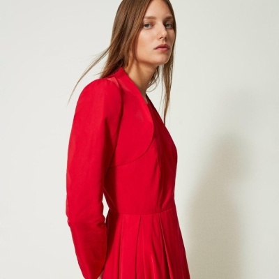 Vestido vermelho de mangas compridas e saia com pregas em fundo branco