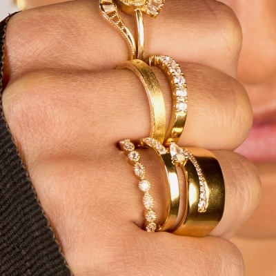 Mão com cinco anéis dourados com pedras brilhantes