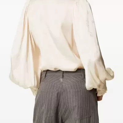 Camisa branca com padrão floral sutil e calças cinzentas riscas verticais em fundo branco