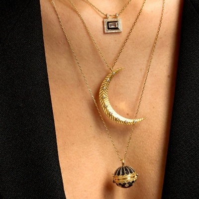 Colares dourados com três pendentes distintos em mulher com roupa preta