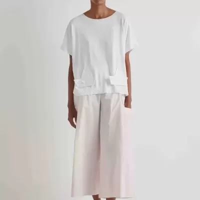 Modelo a usar t-shirt branca de manga curta e calças largas creme com sapatos brancos de salto