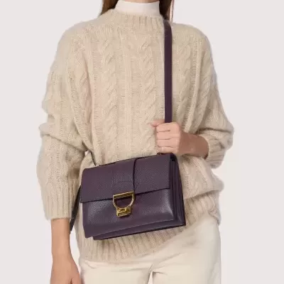 Mulher com camisola bege e mala de mão roxa