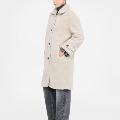 mulher a usar casaco comprido bege em tecido tipo pelo com botões frontais