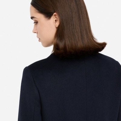 Casaco feminino escuro visto de costas com cabelo castanho liso