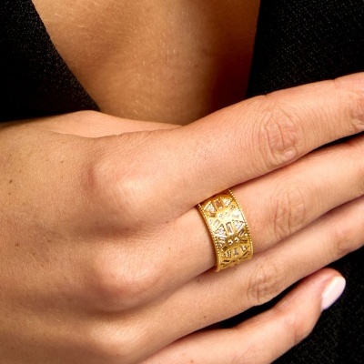 Anel dourado largo com padrão geométrico recortado no dedo médio