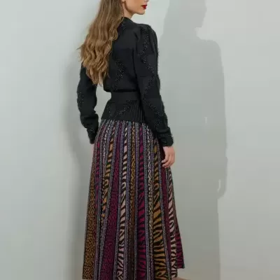Mulher de costas com camisola preta e saia plissada colorida com padrão animal