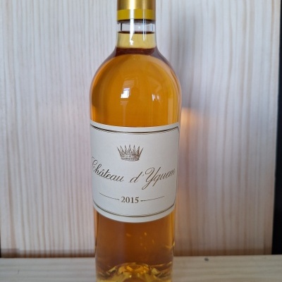 Garrafa de vinho Château d'Yquem 2015 com rótulo branco e tampa dourada em madeira clara
