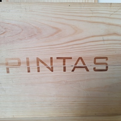Caixa de madeira clara com palavra PINTAS gravada na tampa