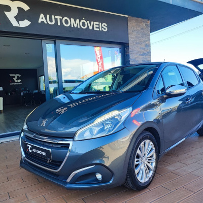 Carro Peugeot cinzento escuro em frente a loja RC AUTOMÓVEIS com porta traseiro aberto