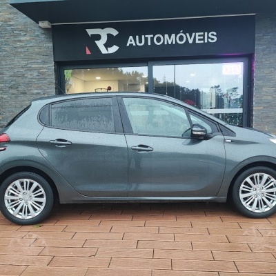 Carro cinza estacionado em frente a loja RC AUTOMÓVEIS