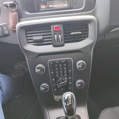 Painel de carro com ecrã digital, comandos de rádio e manete de velocidades automática com revestimento em couro preto.