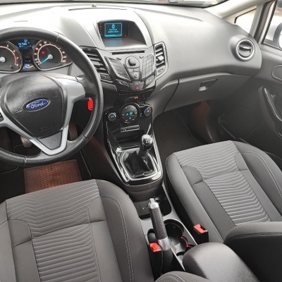 Interior de carro Ford com volante preto e bancos cinzentos em tecido