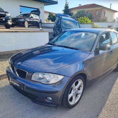 Carro BMW cinza escuro estacionado na rua perto de casa