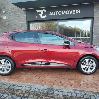 Carro compacto hatchback vermelho estacionado em frente a loja RC AUTOMÓVEIS.