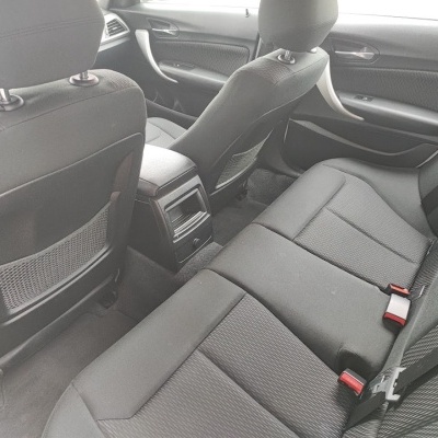 Bancos traseiros de carro cinza escuro em tecido com cintos de segurança e consola central
