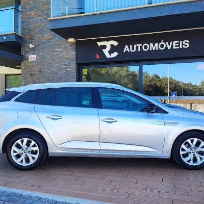Carrinha prateada estacionada frente a edifício com placas de empresa automóvel