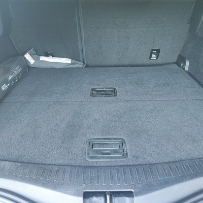 Bagageira de automóvel forrada a carpete cinza escuro com pegas embutidas e kit de primeiros socorros