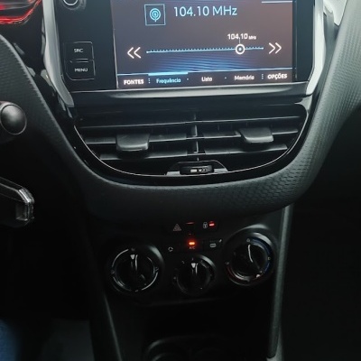 Painel central de automóvel com ecrã de rádio FM 104.10 MHz e comandos de ar condicionado