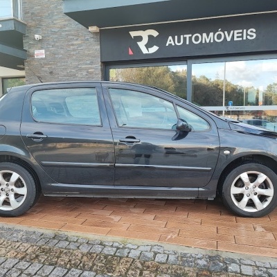 Carro preto de cinco portas estacionado em frente a loja RC AUTOMÓVEIS