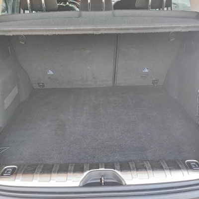 Bagageira de automóvel forrada a tecido cinzento escuro com rede lateral e luz