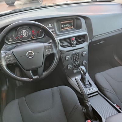 Interior de carro Volvo com volante em couro, painel digital e bancos pretos.