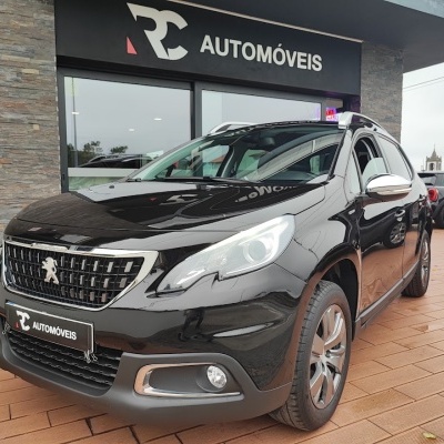 Carro Peugeot preto em loja RC AUTOMÓVEIS com piso tijoleira e parede pedra cinza