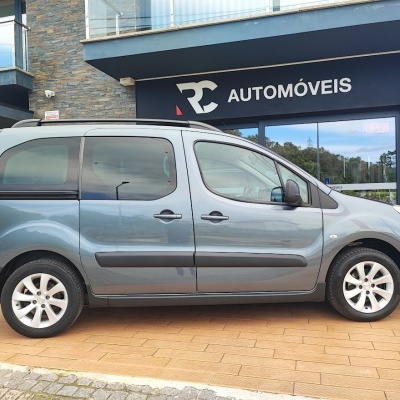 Carro cinza estacionado em frente a uma loja com placa RC AUTOMÓVEIS
