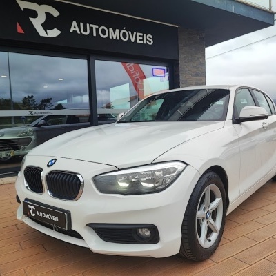 Carro BMW branco parado em frente a loja automóveis