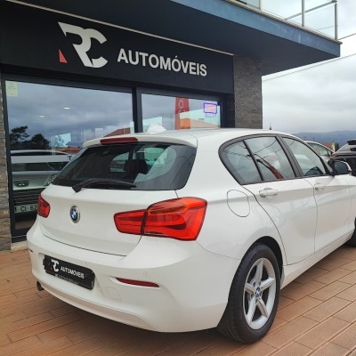 Carro BMW branco de cinco portas junto a loja RC Automóveis
