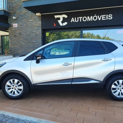 Carro SUV branco parado em frente a loja RC AUTOMÓVEIS com vidro e placa preta