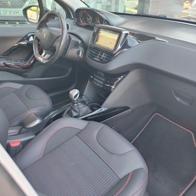 Interior de carro Peugeot com volante, bancos e painel preto com detalhes vermelhos