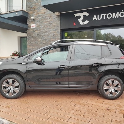 Carro preto estacionado em piso de madeira em frente a loja RC AUTOMÓVEIS