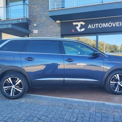 Carro SUV cinza escuro estacionado em frente a loja RC Automóveis