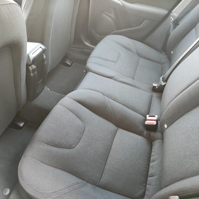 Assento traseiro de carro estofado cinza escuro com cintos de segurança e carpete preto