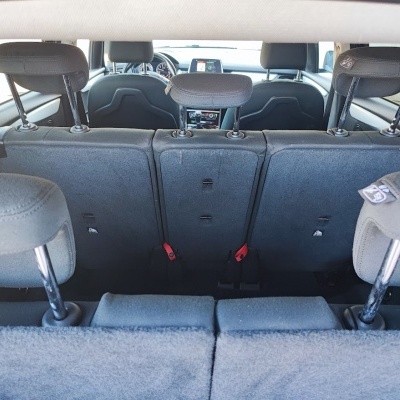 Interior traseiro de carro com bancos em tecido cinza e cintos de segurança