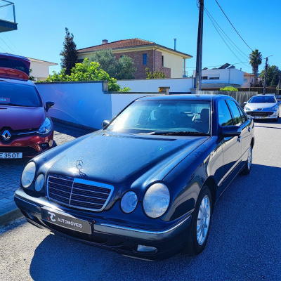 Carro preto Mercedes-Benz estacionado com carro vermelho Renault ao fundo