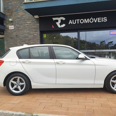Carro branco BMW estacionado em frente à loja RC AUTOMÓVEIS