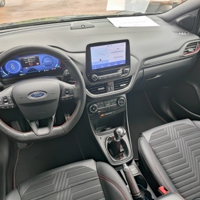 Interior carro Ford com volante couro preto, painel digital azul e bancos preta com costura vermelha