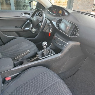 Interior de carro Peugeot com bancos cinza e volante de couro preto