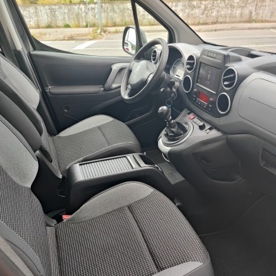 Interior de carro Peugeot com assentos e painel em tecido e plástico cinzento, volante com logótipo Peugeot e sistema de infoentretenimento.
