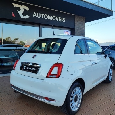 Carro Fiat branco com RC AUTOMÓVEIS ao fundo