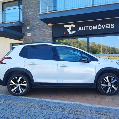 Carro branco com detalhes pretos estacionado em frente a loja RC AUTOMÓVEIS