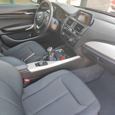 Interior de carro BMW com assentos e volante pretos e consola prateada