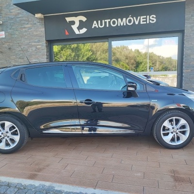 Carro preto compacto cinco portas estacionado em frente a loja RC AUTOMÓVEIS